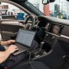 Tehnician cu laptop de configurare conectat la mufa OBD, în timpul codării modulelor unei mașini