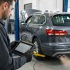 Tehnician cu tabletă de diagnoză lângă o mașină diesel în timpul regenerării filtrului de particule