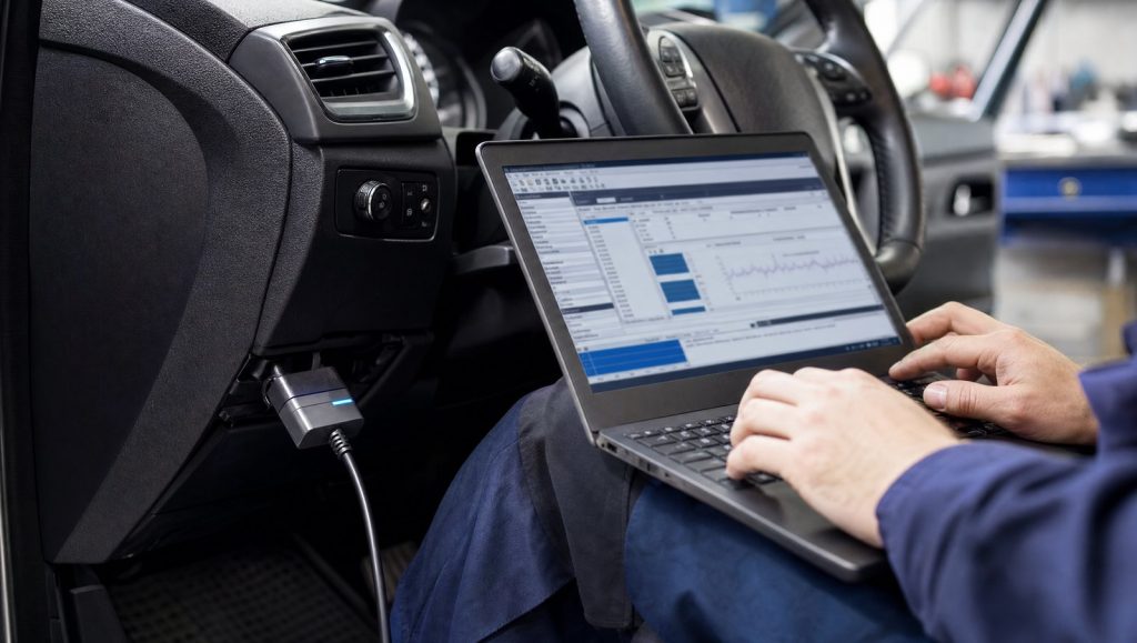 Laptop cu software de diagnoză și adaptor OBD conectat la bordul unui Ford, într-un service