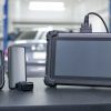 Comparație testere auto: cititor de coduri ieftin și telefon cu dongle lângă o tabletă de diagnoză profesională