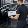 Tehnician cu laptop de diagnoză conectat la un Opel compact în service